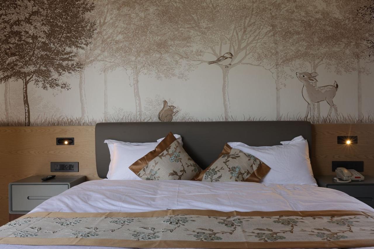 Guest suite bed with sepia forest and fawn mural headboard
