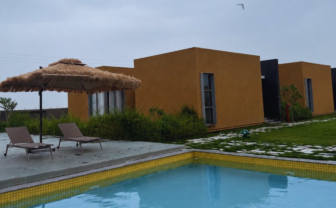 Swimming pool, thatched umbrellas and cabins at The Golden Grass Resort