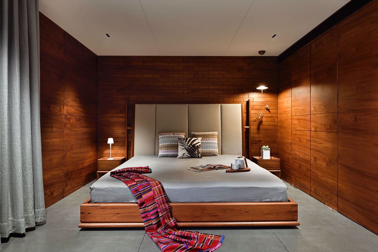 MA HOME primary bedroom lined in teak with a tall upholstered headboard and timber bed
