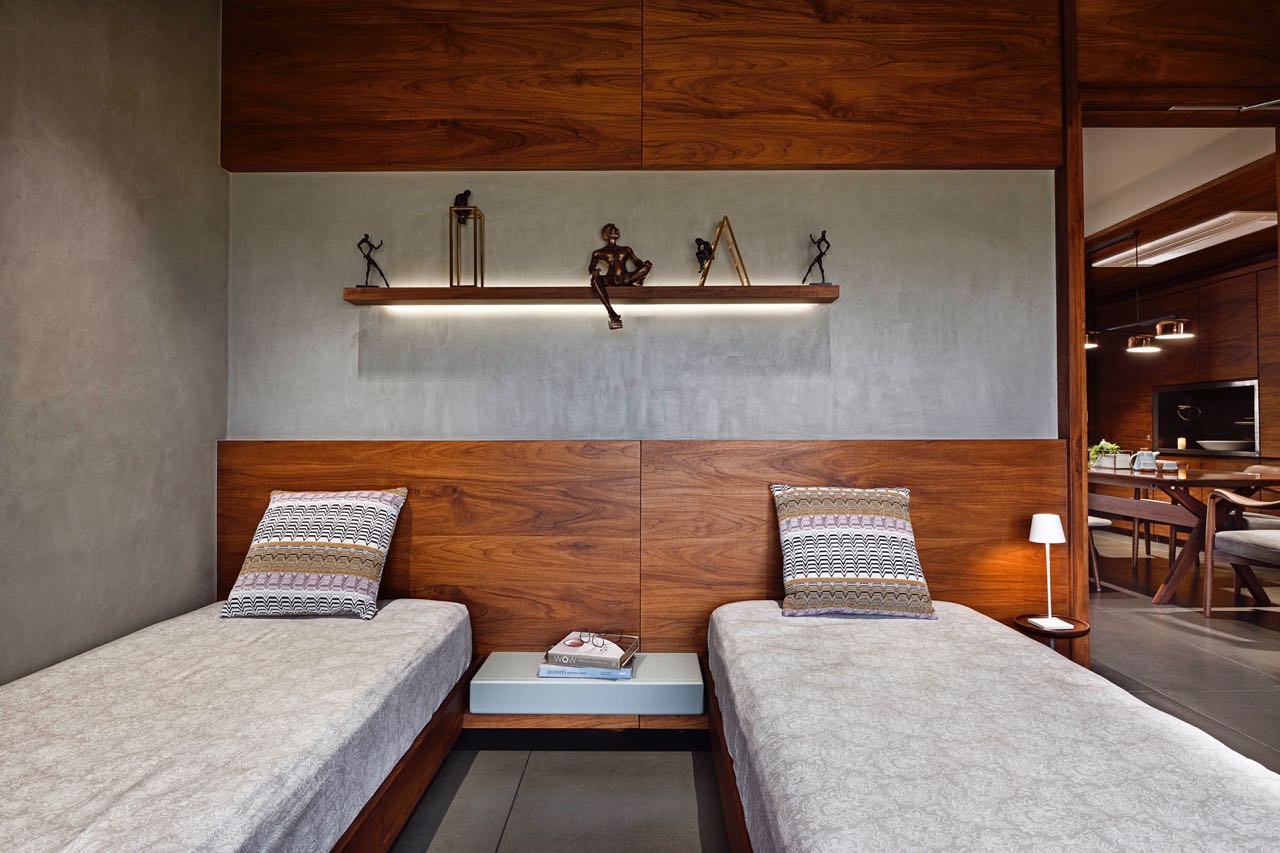 MA HOME twin bedroom with teak headboard wall and a lit shelf of bronze figures