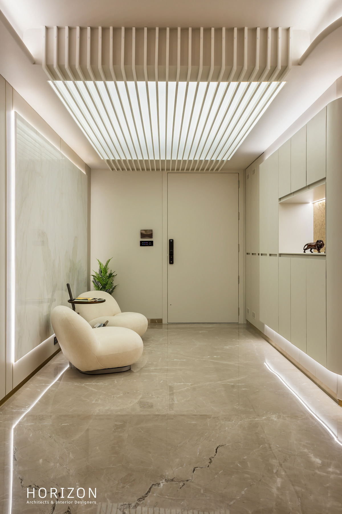 RAHUL BHAI HOME foyer under a slatted backlit ceiling with a boucle lounge chair and framed artwork