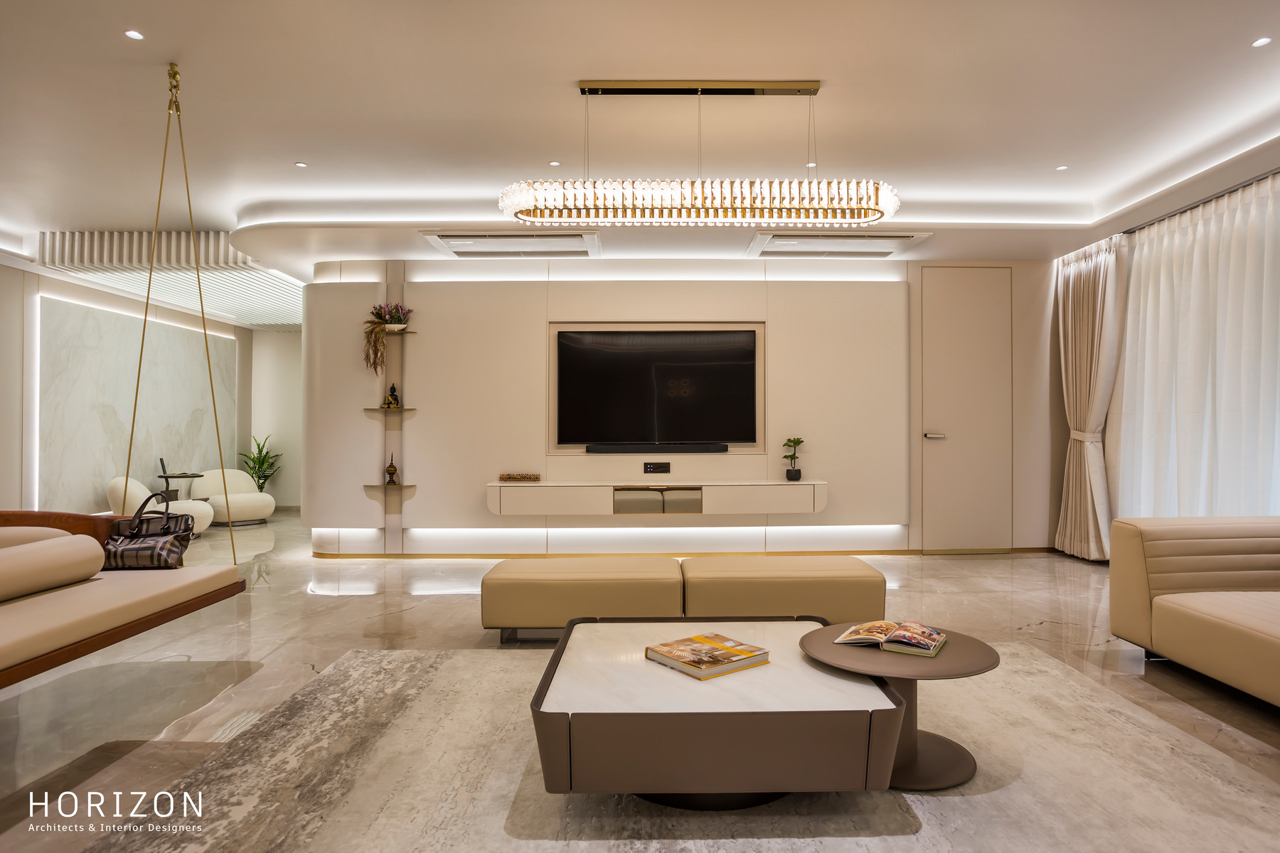 RAHUL BHAI HOME living room with cream sofas, linear crystal chandelier, timber swing and wall-mounted TV
