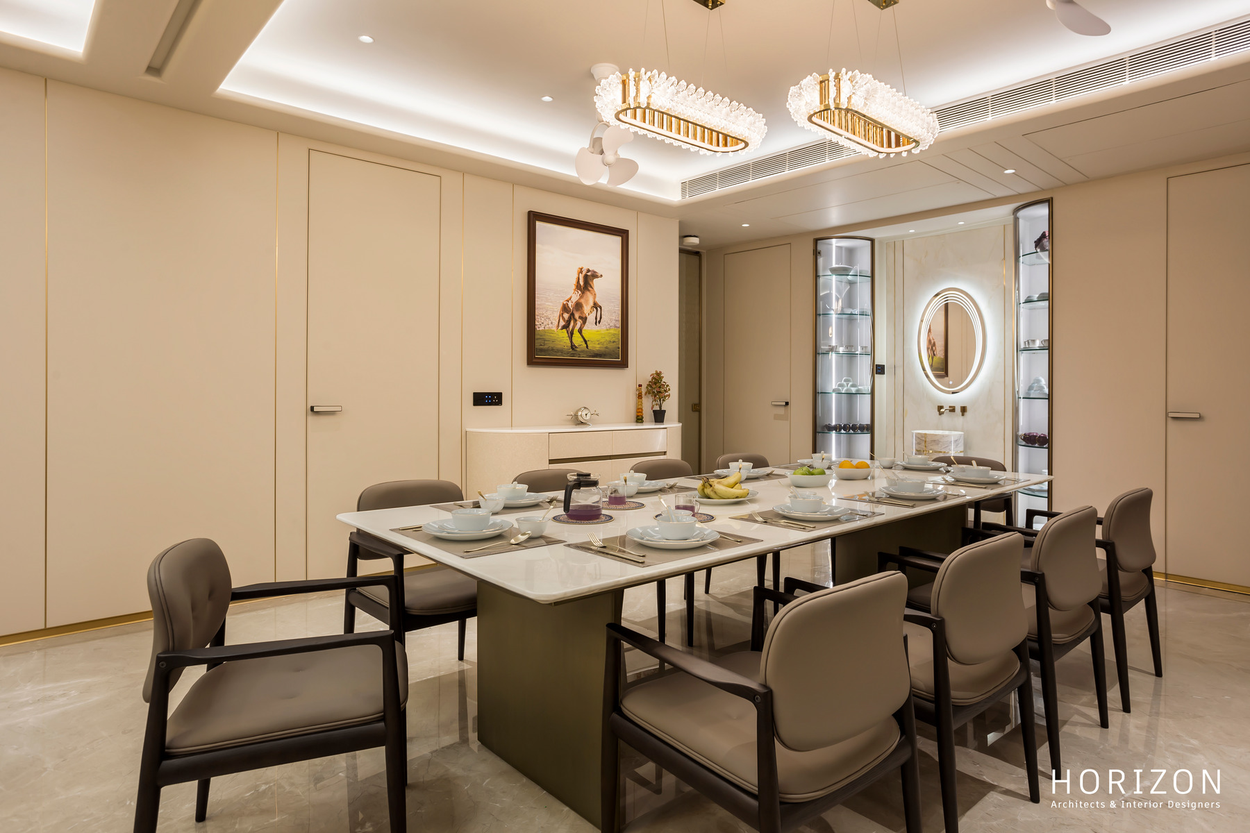 RAHUL BHAI HOME marble dining table with grey upholstered chairs, horse artwork and a lit oval mirror niche