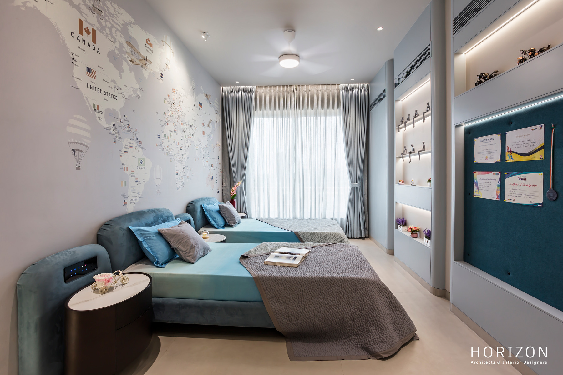 RAHUL BHAI HOME kids' room with world-map wallpaper, blue upholstered bed, pinboard and lit shelves