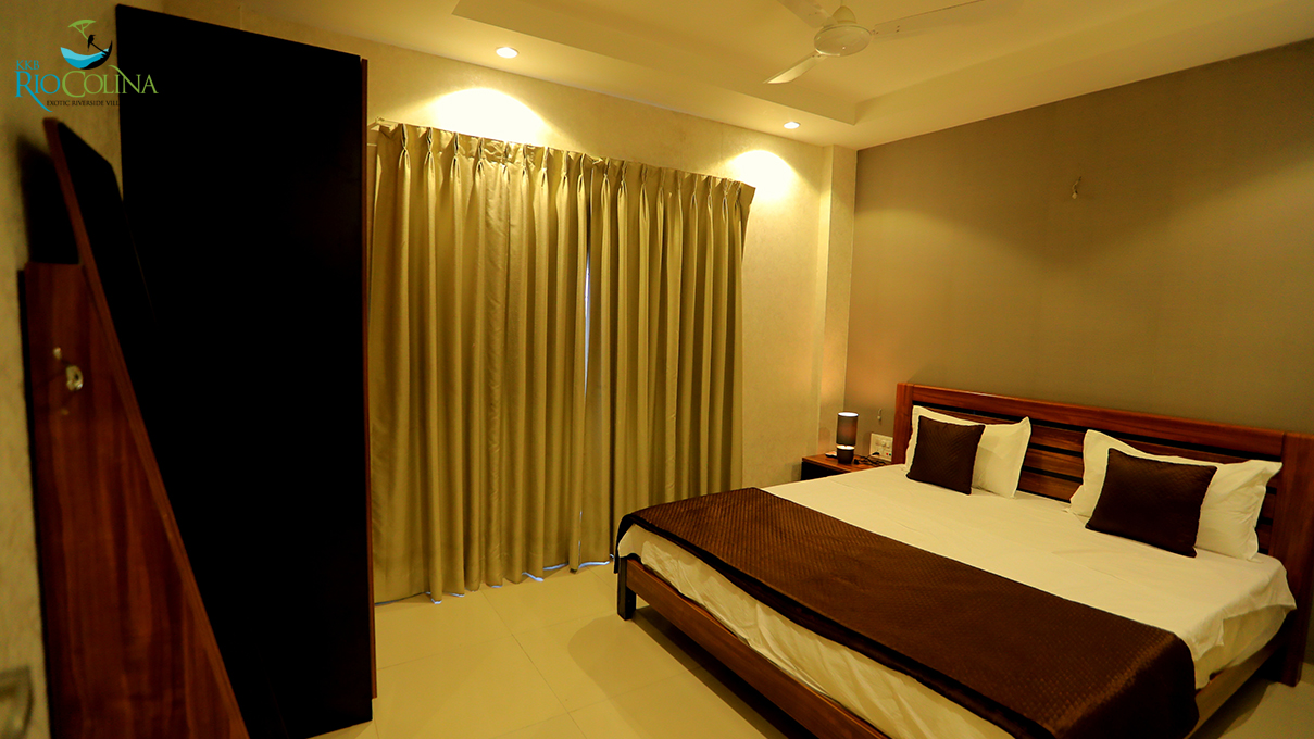 Villa bedroom with timber bed, dark wardrobe and gold curtains