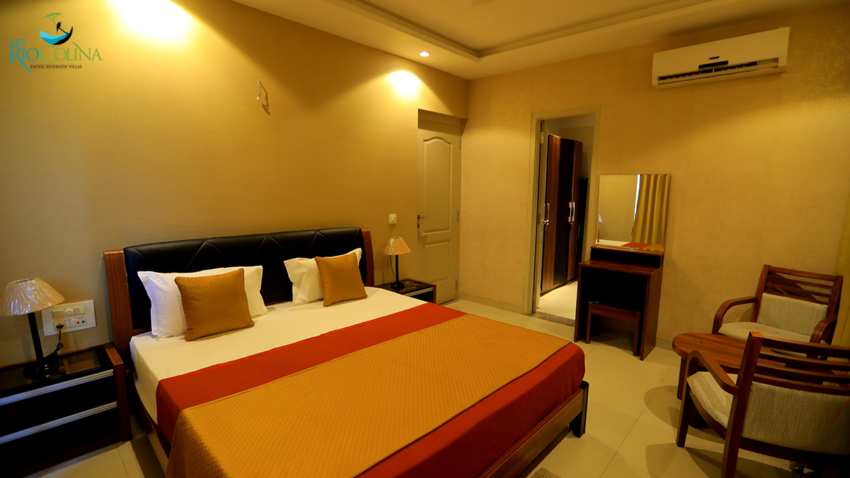 Villa guest bedroom with orange bedspread and dressing table