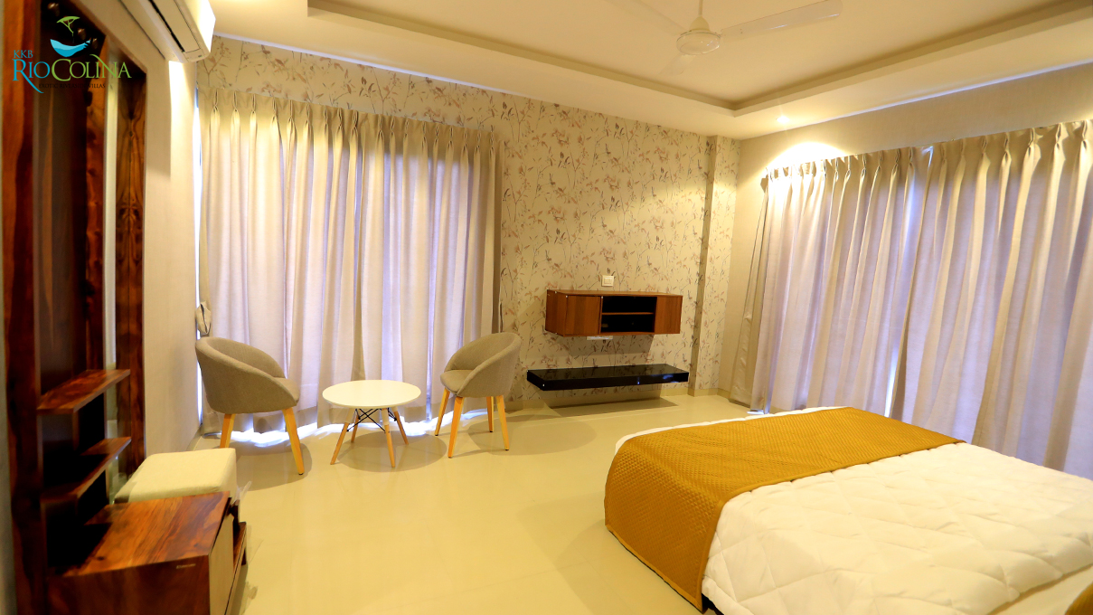 Villa bedroom with mustard bedspread, armchairs and floral wallpaper