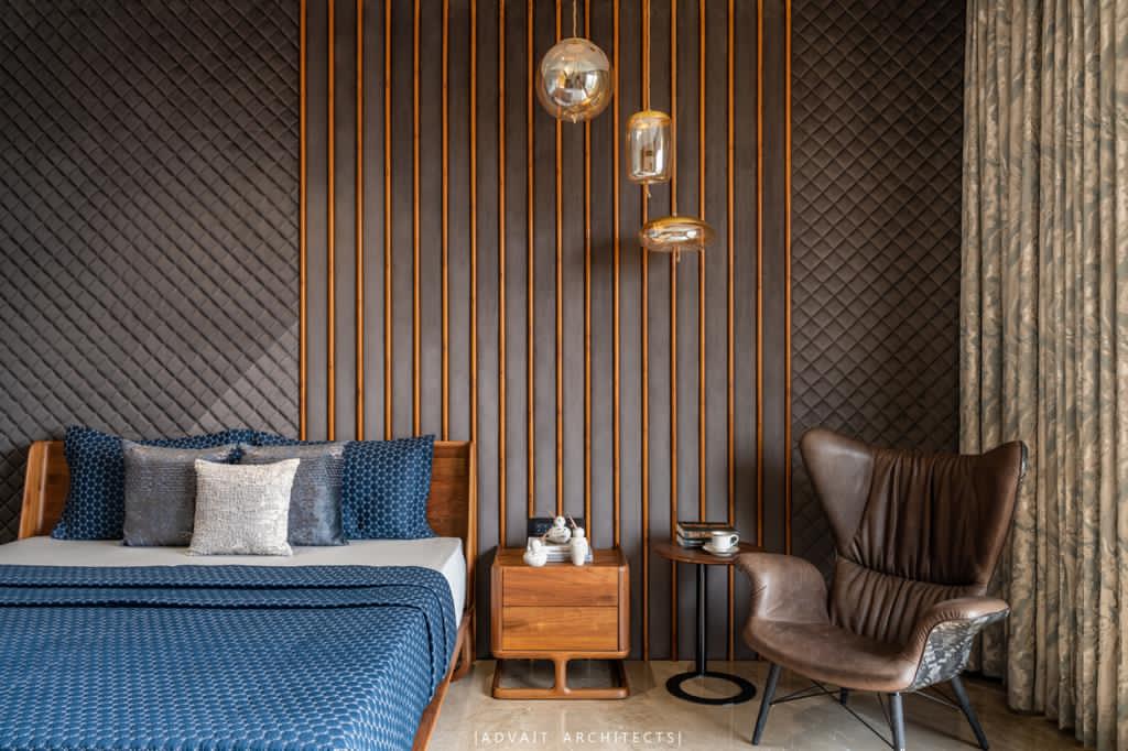 VILLASHBHAI HOME bedroom with slatted panelling, blue bedding and a leather reading chair