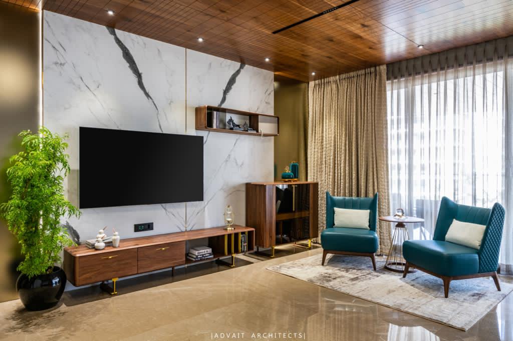 VILLASHBHAI HOME bedroom with marble media wall, teal armchairs and a curtained window