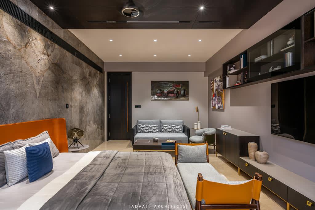 VILLASHBHAI HOME bedroom with concrete-toned walls, orange headboard and a corner sofa