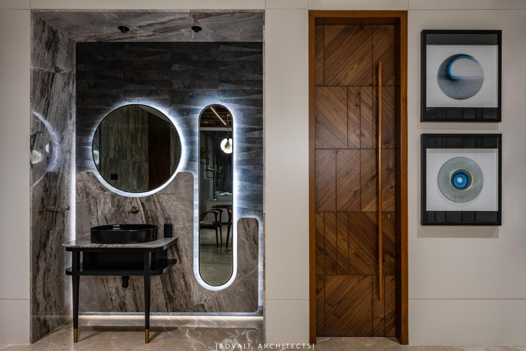 VILLASHBHAI HOME dressing area with a lit round mirror, dark vanity and framed prints